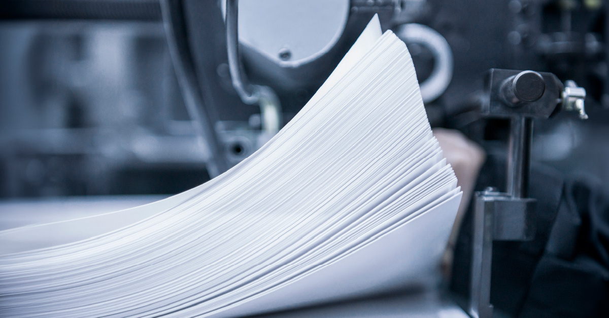 A stack of papers getting processed through a production printer.