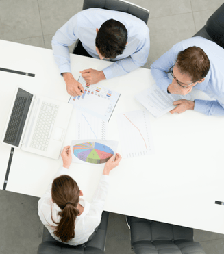 A group of workers compares the features and benefits of cloud voice vs. unified communications in a boardroom. 